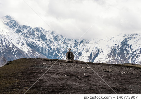 A view of Mount Kazbek in Georgia. A small stone chapel with a cross is visible in the foreground A view of Mount Kazbek in Georgia. A small stone chapel with a cross is visible in the foreground 140775907