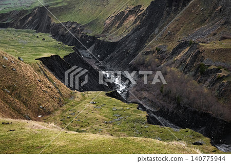 a deep canyon with a narrow river flowing along its rocky bottom 140775944