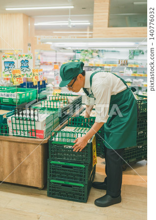 A male supermarket employee setting up the vegetable section. A male supermarket employee setting up the vegetable section. 140776032