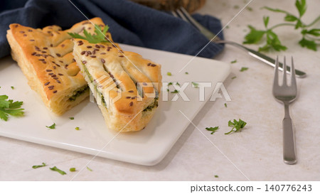 Savory puff pastry slices with green herb filling on a plate Savory puff pastry slices with green herb filling on a plate 140776243