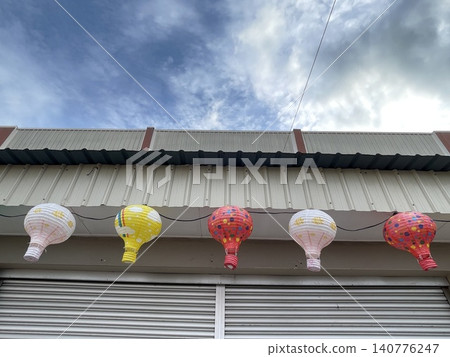 Front View Of Hot Air Balloon Shaped Lanterns Hanging Under Eaves 140776247