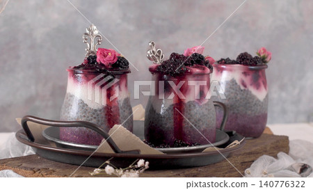 Layered blackberry chia pudding jars with edible flowers Layered blackberry chia pudding jars with edible flowers 140776322