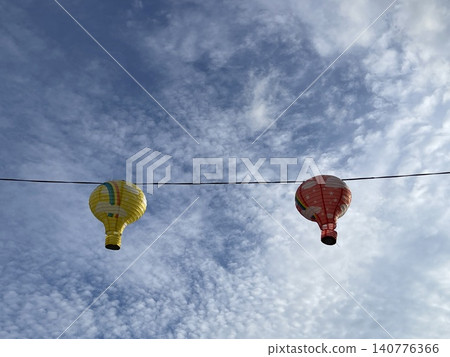 Two Hot Air Balloon Shaped Lanterns Hanging On Wire Against Sky Two Hot Air Balloon Shaped Lanterns Hanging On Wire Against Sky 140776366