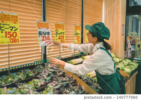 女店員正在蔬菜區佈置促銷展示架 女店員正在蔬菜區佈置促銷展示架 140777060