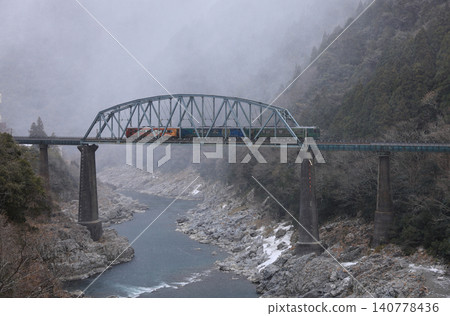 Snow is approaching from the north as the No. 2 Yoshino River Bridge in the Oboke Gorge passes over it by JR Shikoku's sightseeing train, "Shikoku Mannaka Sennen Monogatari". Snow is approaching from the north as the No. 2 Yoshino River Bridge in the Oboke Gorge passes over it by JR Shikoku's sightseeing train, "Shikoku Mannaka Sennen Monogatari". 140778436