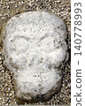 Stone rock skull face in gravel ground 140778993