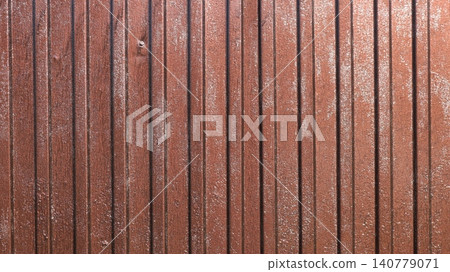 Brown vertical corrugated sheeting with an aged texture. The metal sheet surface is covered with small light abrasions, patina, and signs of wear. Traces of condensation on the textured iron fence. Brown vertical corrugated sheeting with an aged texture. The metal sheet surface is covered with small light abrasions, patina, and signs of wear. Traces of condensation on the textured iron fence. 140779071