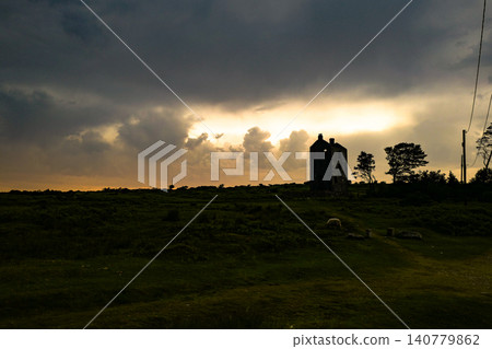 This dramatic scene depicts a stormy sunset with clouds breaking to reveal golden light. The atmosphere resembles a rare optical weather phenomenon, where sunset colours glow behind dark storm clouds This dramatic scene depicts a stormy sunset with clouds breaking to reveal golden light. The atmosphere resembles a rare optical weather phenomenon, where sunset colours glow behind dark storm clouds 140779862