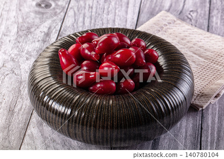 Red berries in textured dark bowl on rustic wooden surface Red berries in textured dark bowl on rustic wooden surface 140780104