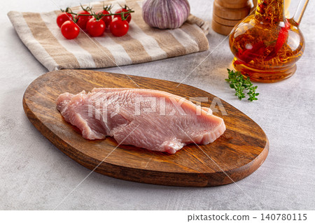 Raw turkey breast on wooden cutting board with cherry tomatoes garlic and herb oil 140780115