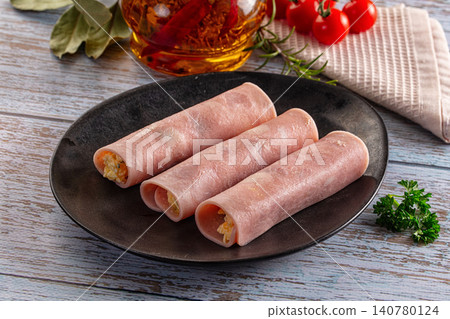 Ham rolls with cheese filling on dark plate with herbs and cherry tomatoes Ham rolls with cheese filling on dark plate with herbs and cherry tomatoes 140780124