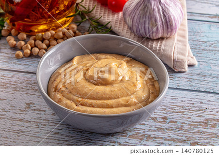 Creamy hummus in gray bowl with chickpeas garlic olive oil and rosemary on rustic wooden table Creamy hummus in gray bowl with chickpeas garlic olive oil and rosemary on rustic wooden table 140780125