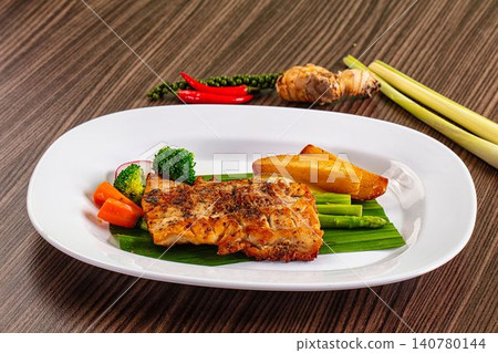 Grilled crocodile fillet with asparagus carrots and potato wedges on banana leaf Grilled crocodile fillet with asparagus carrots and potato wedges on banana leaf 140780144