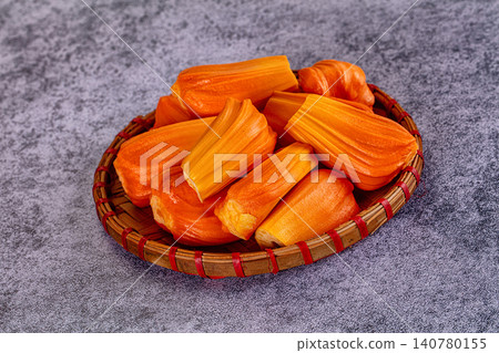 Fresh jackfruit segments in woven basket on textured gray surface Fresh jackfruit segments in woven basket on textured gray surface 140780155