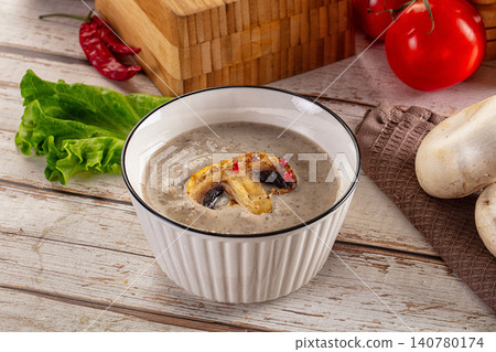 Creamy mushroom soup in white bowl with fresh ingredients on rustic wooden table Creamy mushroom soup in white bowl with fresh ingredients on rustic wooden table 140780174