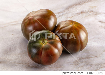 Three dark heirloom tomatoes on marble surface Three dark heirloom tomatoes on marble surface 140780178