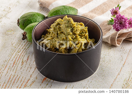 Green fruit paste in dark bowl with whole fruits and purple flowers on rustic wood Green fruit paste in dark bowl with whole fruits and purple flowers on rustic wood 140780186