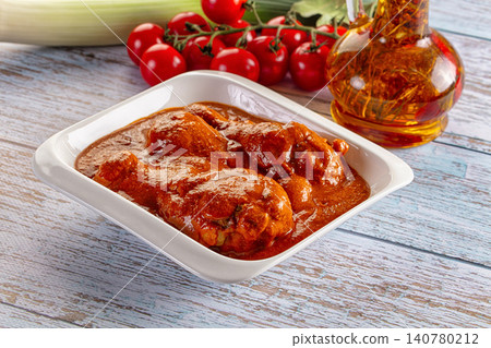 Chicken in rich tomato sauce served in white dish with cherry tomatoes and oil bottle on rustic wooden table Chicken in rich tomato sauce served in white dish with cherry tomatoes and oil bottle on rustic wooden table 140780212