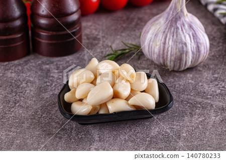 Garlic cloves in black bowl with whole bulb and rosemary on stone surface Garlic cloves in black bowl with whole bulb and rosemary on stone surface 140780233