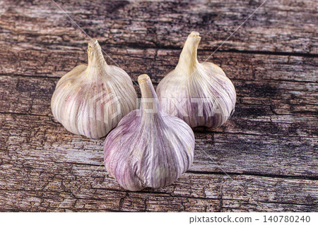 Three garlic bulbs on rustic wooden surface Three garlic bulbs on rustic wooden surface 140780240