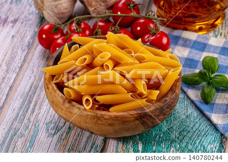 Penne pasta in wooden bowl with cherry tomatoes and basil on rustic table Penne pasta in wooden bowl with cherry tomatoes and basil on rustic table 140780244