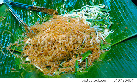 Top view of traditional Pad Thai noodles served on fresh green banana leaf at a Thai street food market. Top view of traditional Pad Thai noodles served on fresh green banana leaf at a Thai street food market. 140780494
