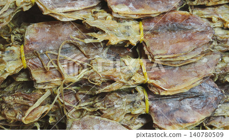 Close-up of dried squids tied with yellow rubber bands, full frame background of traditional Thai sun-dried cuttlefish bundles. Close-up of dried squids tied with yellow rubber bands, full frame background of traditional Thai sun-dried cuttlefish bundles. 140780509