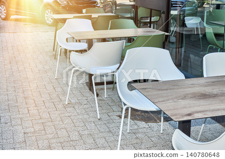 Empty tables on cafe terrace. White and green chairs outdoor. Sidewalk restaurant patio setup. Empty tables on cafe terrace. White and green chairs outdoor. Sidewalk restaurant patio setup. 140780648