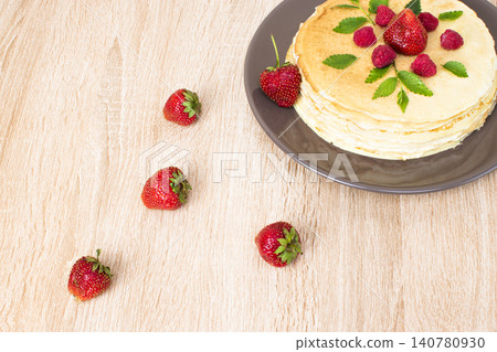 Pancakes with strawberries and raspberries. Pancakes with raspberries and strawberries on a plate. Pancakes with raspberries and strawberries on a plate and a wooden board. Pancakes with strawberries and raspberries. Pancakes with raspberries and strawberries on a plate. Pancakes with raspberries and strawberries on a plate and a wooden board. 140780930