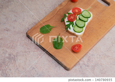 Vegan sandwiches with homemade curd cream with herbs, with radishes, cucumbers and tomatoes. On wooden cutting board. Vegan sandwiches with homemade curd cream with herbs, with radishes, cucumbers and tomatoes. On wooden cutting board. 140780935
