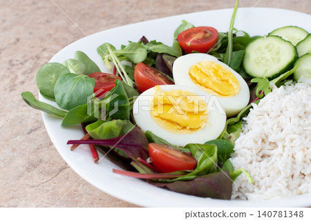 Salad of green vegetables, tomato and rice in a white plate. Rice with vegetables and eggs on a white plate. Salad of green vegetables, tomato and rice in a white plate. Rice with vegetables and eggs on a white plate. 140781348