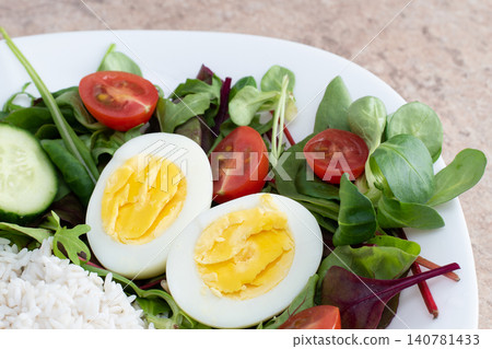 Salad of green vegetables, tomato and rice in a white plate. Rice with vegetables and eggs on a white plate. Salad of green vegetables, tomato and rice in a white plate. Rice with vegetables and eggs on a white plate. 140781433