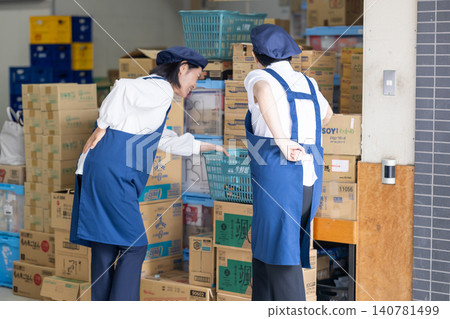 A part-time worker in her 40s clutches her lower back. A part-time worker in her 40s clutches her lower back. 140781499