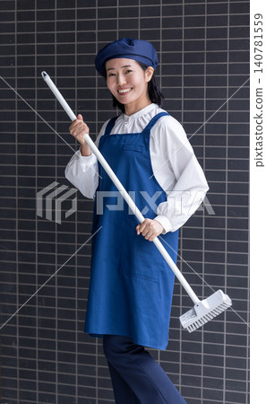 A smiling part-time female staff member holding a mop. 140781559