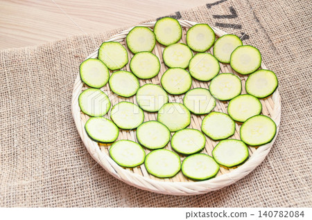 Sliced zucchini are laid out on a sieve to be sun-dried. Sliced zucchini are laid out on a sieve to be sun-dried. 140782084