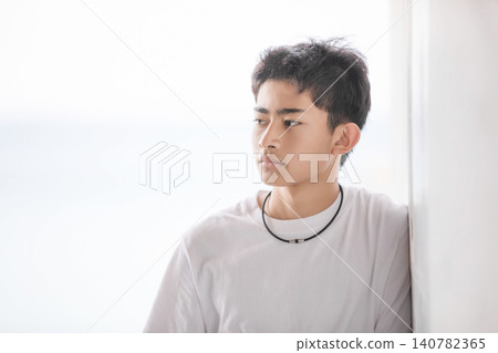 一名十幾歲的年輕男子,身穿白色T卹 一名十幾歲的年輕男子,身穿白色T卹 140782365