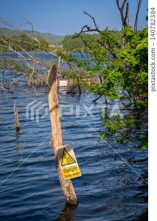Mercers Lake near Merstham, Surrey, UK with trees on a summer's day. A danger sign warns of deep water. Mercers Lake near Merstham, Surrey, UK with trees on a summer's day. A danger sign warns of deep water. 140782384