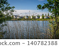 A modern housing development next to the Holmethorpe Lagoons in Mersham, Surrey, UK. Trees and reeds in the foreground. Landscape orientation. 140782388