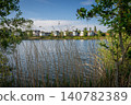 A modern housing development next to the Holmethorpe Lagoons in Mersham, Surrey, UK. Trees and reeds in the foreground. Landscape orientation. 140782389