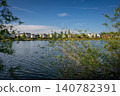 A modern housing development next to the Holmethorpe Lagoons in Mersham, Surrey, UK. Trees in the foreground. Landscape orientation. 140782391