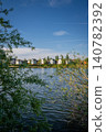 A modern housing development next to the Holmethorpe Lagoons in Mersham, Surrey, UK. Trees in the foreground. Portrait orientation. 140782392