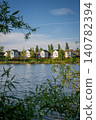 A modern housing development next to the Holmethorpe Lagoons in Mersham, Surrey, UK. Trees in the foreground. Portrait orientation. 140782394