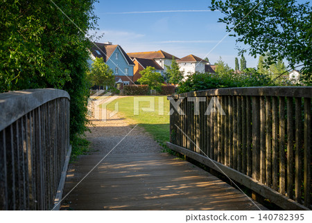 A modern housing development in Mersham, Surrey, UK. A path over a small wooden bridge leads to the houses. A modern housing development in Mersham, Surrey, UK. A path over a small wooden bridge leads to the houses. 140782395
