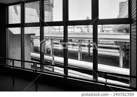 A black and white photo of the "station platform" seen through a window inside JR Naebo Station. A black and white photo of the "station platform" seen through a window inside JR Naebo Station. 140782399