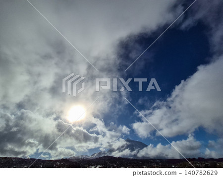 Sunlit mountain landscape under dramatic cloudy sky Sunlit mountain landscape under dramatic cloudy sky 140782629