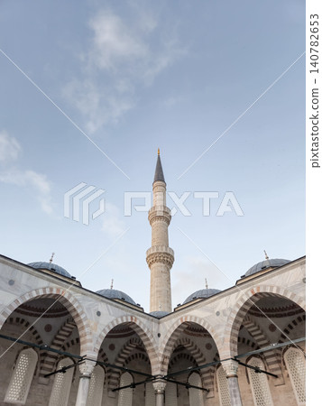 Islamic mosque courtyard with tall minaret and arches 140782653