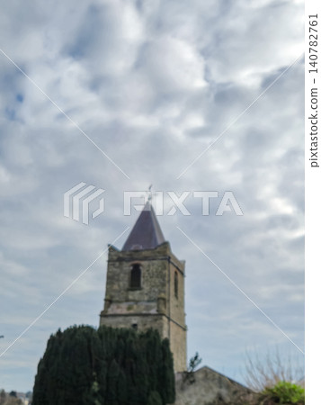 Historic stone church tower beneath cloudy sky Historic stone church tower beneath cloudy sky 140782761