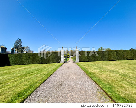 Formal garden path leading to gated hedge entrance Formal garden path leading to gated hedge entrance 140782785