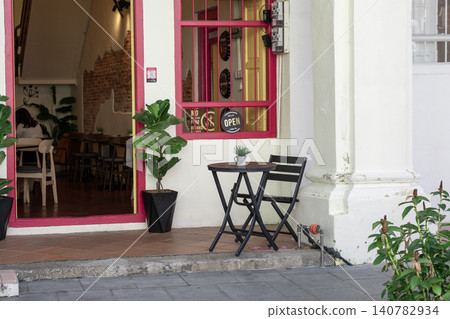 Small outdoor cafe table and chairs by colorful storefront entrance Small outdoor cafe table and chairs by colorful storefront entrance 140782934