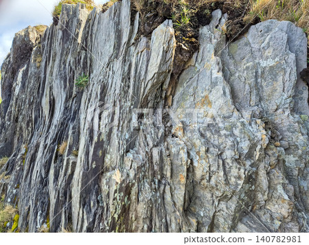 Layered rocky cliff face with weathered stone texture Layered rocky cliff face with weathered stone texture 140782981